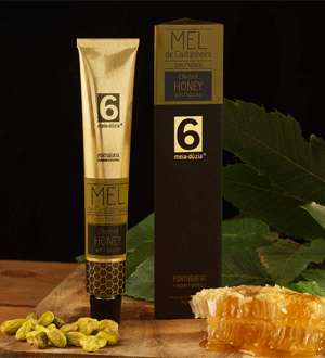 Tube of Chestnut Honey from the Portuguese brand 6 MEIA-DÚZIA®, displayed alongside its original packaging, a piece of honeycomb and chestnuts, on a wooden surface.