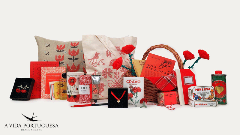 Coleção de produtos tradicionais portugueses inspirados no 25 de abril apresentados pela marca portuguesa A Vida Portuguesa, incluindo itens de decoração como uma almofada bordada, artigos de papelaria, conservas Minerva e joias temáticas.