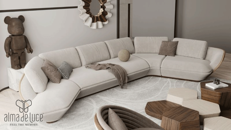 Sala de estar contemporânea com sofá modular curvo em tons claros, mesas de apoio em madeira e peças de design da marca portuguesa ALMA DE LUCE®.