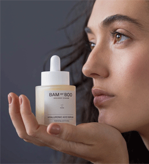Frasco cilíndrico de vidro fosco com doseador conta-gotas branco pertence ao Sérum de Ácido Hialurónico da marca de cosmética sustentável BAM AND BOO GROUNDED SKINCARE®, destacando-se pelo rótulo minimalista em tons de branco e preto.