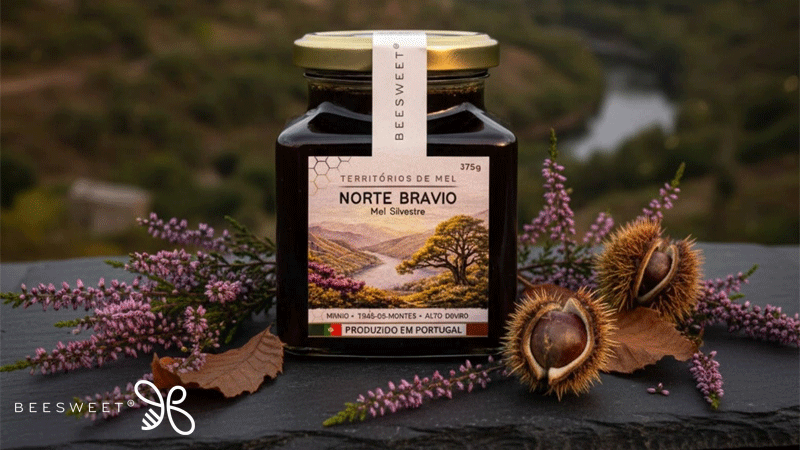 Frasco de 375 g de mel silvestre NORTE BRAVIO da marca portuguesa BEESWEET®, sobre ardósia, rodeado de urze e ouriços de castanha.