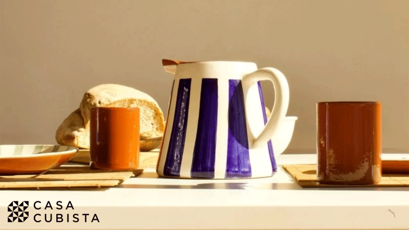 Jarro modelo Bold Stripe da marca portuguesa Casa Cubista, conhecido pelo seu design de riscas azuis pintadas à mão sobre cerâmica branca, e outras peças em cerâmica da mesma marca.
