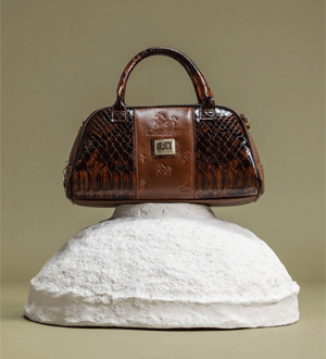 Mala de mão média estilo bowling numa mistura de pele envernizada e genuína, na cor camel da marca portuguesa Cavalinho.