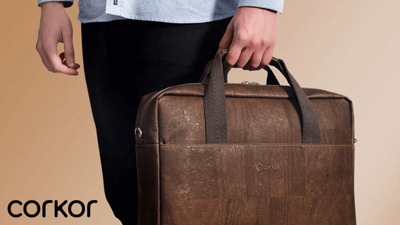 Pessoa a segurar uma mala de trabalho em cortiça castanha da marca portuguesa CORKOR®, com alças escuras.