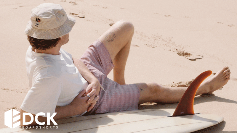 Homem deitado na areia na praia usando calções de banho de homem da marca portuguesa DCK.