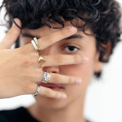 Rapariga com mão a tapar o rosto e os dedos cheios de anéis