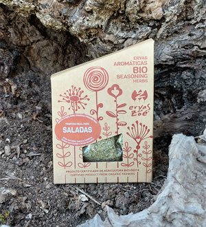 Embalagem de ervas aromáticas biológicas para saladas da marca portuguesa ERVAS DA ZOÉ®, fotografada entre rochas num ambiente natural.