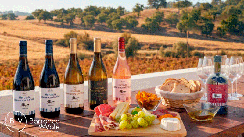 Degustação de vinhos ao ar livre durante o pôr-do-sol na Herdade Barranco do Vale, localizada no Algarve, Portugal. A herdade oferece experiências de enoturismo que incluem provas de vinhos premium e clássicas.