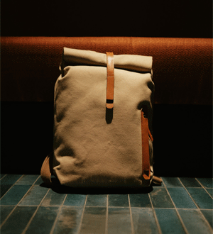 Mochila de design roll-top em lona de cor bege/areia com detalhes em couro castanho da marca portuguesa Ideal & Co.