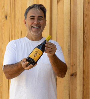 O produtor Romeu Martins a segurar uma garrafa de vinho da Adega Malápio, da região da Bairrada, conhecida pelos seus vinhos de talha tradicionais. 