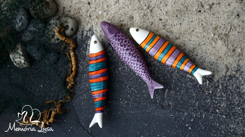 	Sardinhas de cerâmica pintadas à mão pela marca portuguesa Memória Lusa, um ícone do artesanato português e dos Santos Populares. Cada peça é única, com ligeiras variações que refletem o trabalho manual.