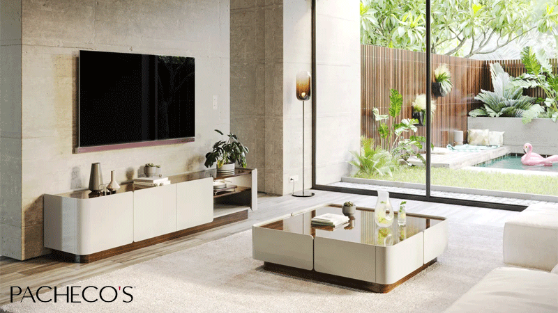 Sala de estar da Coleção Soho da marca portuguesa Pacheco's, composta por um móvel de TV e uma mesa de centro com acabamento lacado bege e detalhes em madeira. 