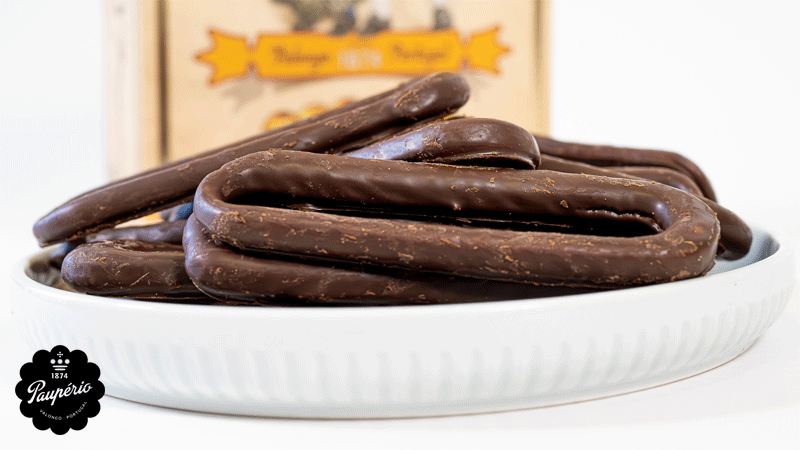 Biscoitos compridos cobertos de chocolate da marca portuguesa PAUPÉRIO®, servidos num prato branco.