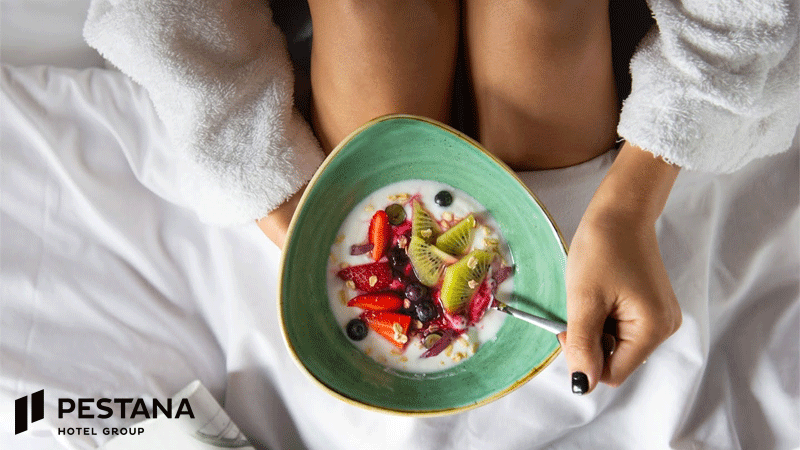 Hóspede da marca portuguesa PESTANA® desfruta de uma taça de fruta fresca com iogurte durante uma experiência de pequeno-almoço no hotel.