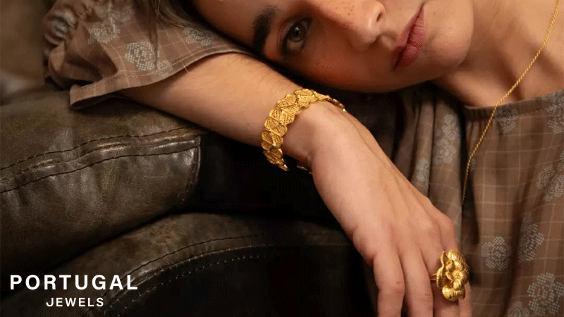 Mulher a usar joias da marca portuguesa Portugal Jewels, nomeadamente, uma pulseira estilo filigrana, com um anel em formato de flor e um colar, todas as joias em prata dourada com banho de ouro.