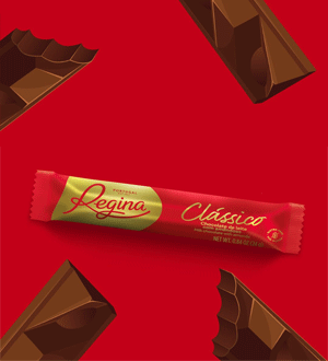 Barra de chocolate de leite Clássico da marca portuguesa REGINA®, apresentada sobre fundo vermelho e rodeada por pedaços de chocolate.