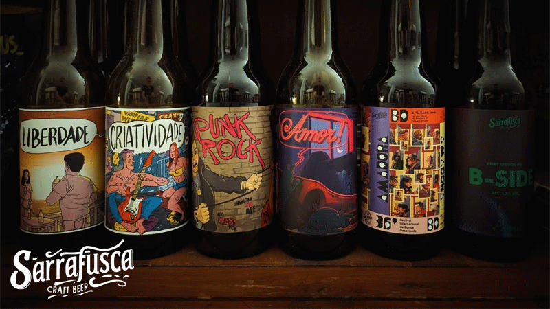 Variedade de garrafas de Sarrafusca Craft Beer, uma marca portuguesa de cerveja artesanal do Oeste de Portugal. Cada garrafa apresenta rótulos distintos com arte ilustrada, incluindo temas como "Liberdade", "Criatividade", "Punk Rock" e "Amor!".