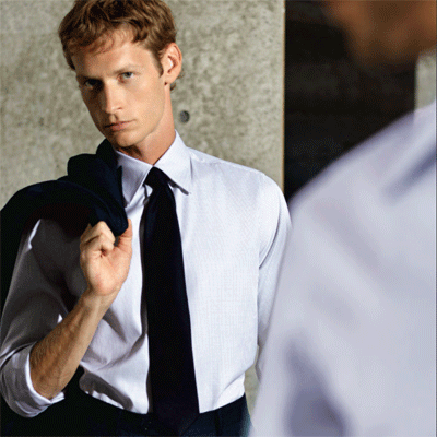 homem jovem elegantemente vestido de camisa e gravata com casaco jovialmente ao ombro