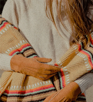 Visual de inverno acolhedor, destacando-se pelas luvas de camurça em tons terra e um cachecol com riscas coloridas vibrantes da marca portuguesa trouxa mocha.