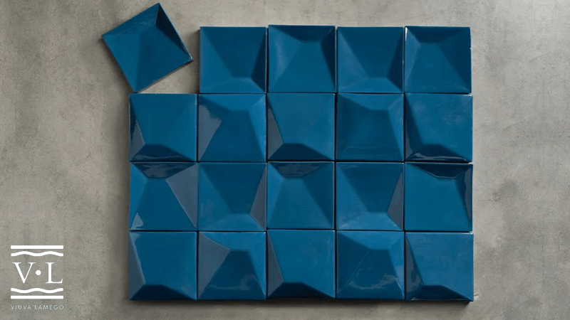 Composição de azulejos azuis tridimensionais da marca portuguesa VIÚVA LAMEGO®, dispostos em grelha sobre uma superfície cinzenta.