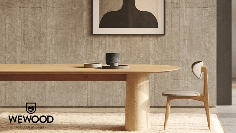 Mesa de jantar oval em madeira e cadeira da marca portuguesa WEWOOD PORTUGUESE JOINERY® num ambiente contemporâneo de tons neutros, com parede texturada, tapete claro e elementos decorativos minimalistas.